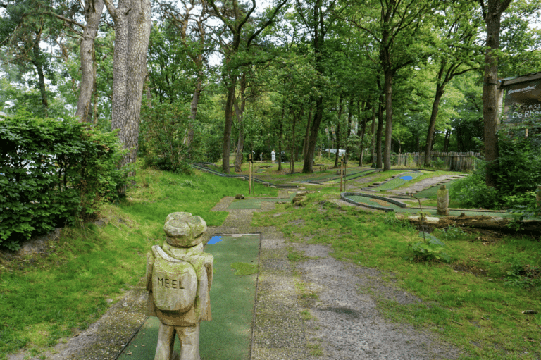 Midgetgolfbaan tussen de bomen met een houten kabouterbeeld