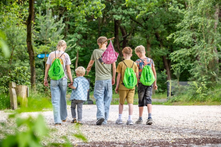 Gezin wandelt met Knof-rugzakjes over een grindpad door het bos bij De Rheezerbelten