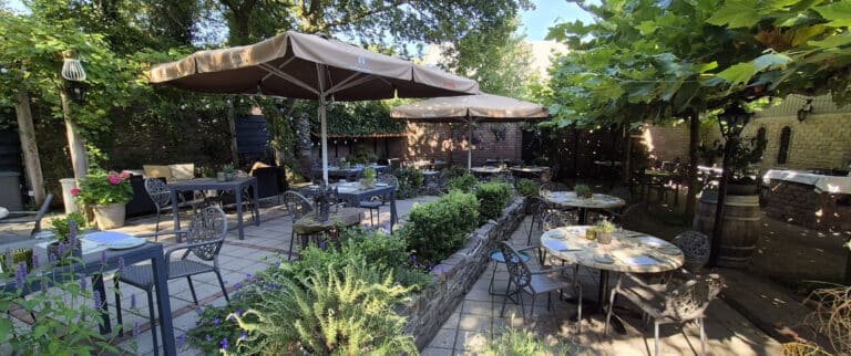Sfeervol terras met parasols en tafeltjes tussen het groen